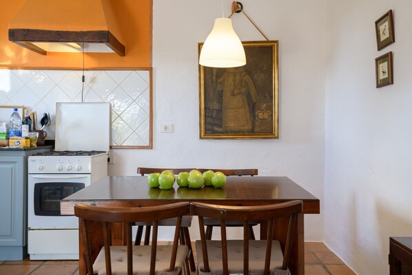 Una cocina con una mesa de comedor, sillas, estufa y una lámpara colgante.