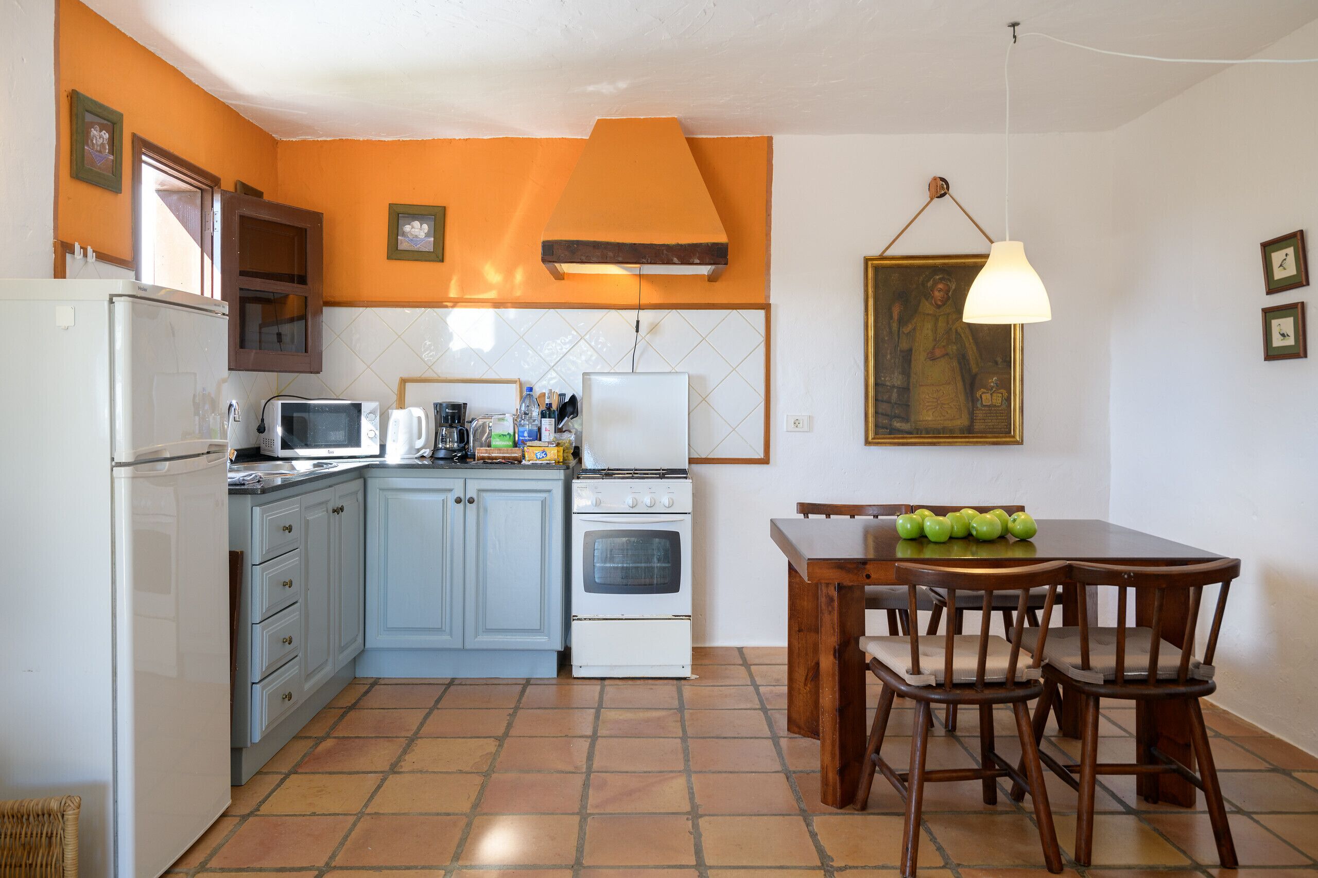 A kitchen with a dining table and chairs, a refrigerator, microwave, stove, and various kitchen items.
