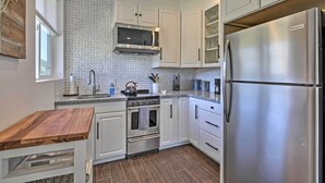 Una cocina moderna con armarios blancos, un refrigerador de acero inoxidable, un horno empotrado y un microondas.