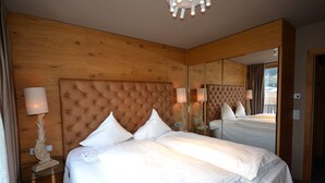 A hotel room with a large bed, wooden paneling, a mirror, and a chandelier.