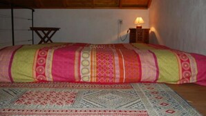 Een slaapkamer met een bed, een houten plafond, een wandlamp en een klein tafeltje.
