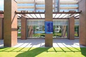 A building with a glass facade, a signboard, and a grassy area in front.