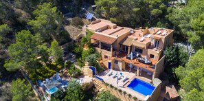 A two-story villa with a swimming pool, outdoor seating, and satellite dishes.
