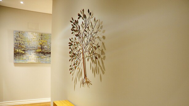 A room with a wooden bench, a wall-mounted tree sculpture, and a painting of a landscape. - Refurbished apartment with air conditioning in the center of Setúbal (Setúbal)