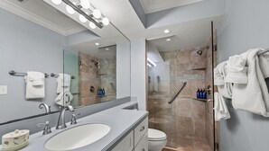 Une salle de bain moderne avec un grand lavabo, un miroir et un espace douche.