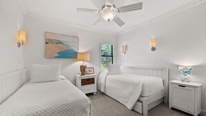 Une chambre avec deux lits, un ventilateur de plafond et des lampes fixées au mur.