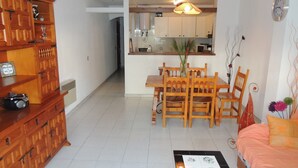 A compact living space with a dining area, kitchenette, and a sofa.