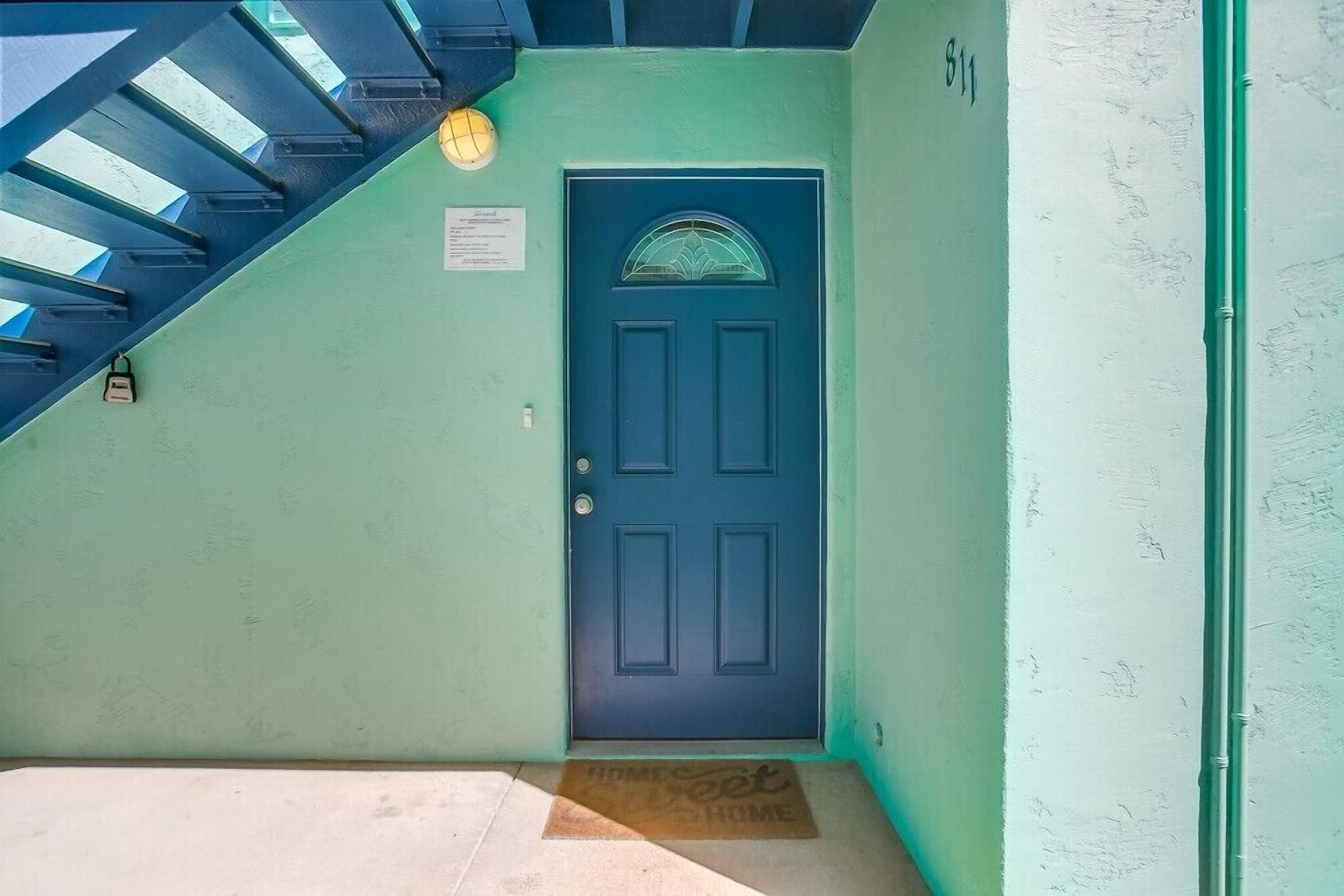 A blue door with a glass panel, a staircase with blue railings, and a green wall with a number '811' visible.