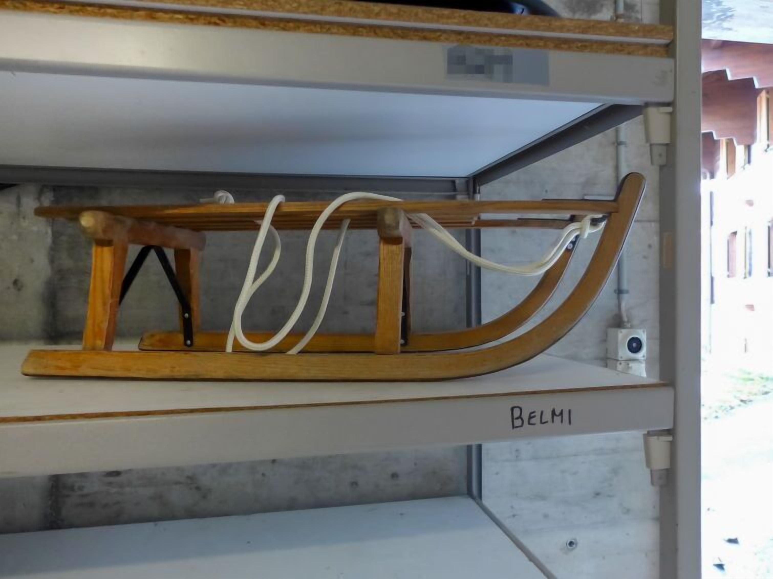 Un trineo de madera sobre una estantería con la etiqueta "BELMI".