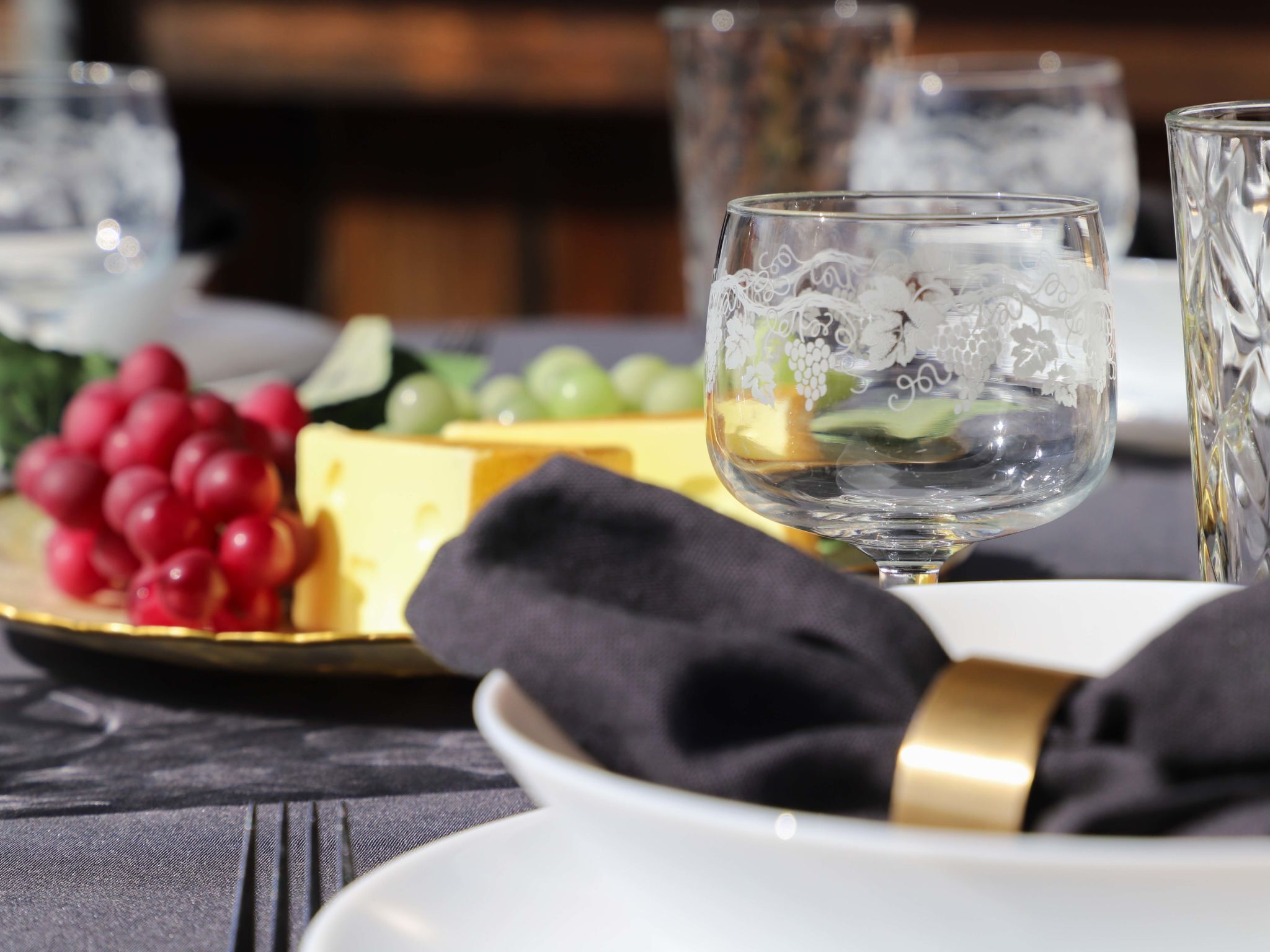 A dining table with a plate of cheese and grapes, a glass of water, and a napkin.