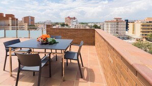 A rooftop terrace with a table and chairs, a brick wall, and a view of the cityscape. - Nice apartment with terrace and pool near the beach and shops Inmosantos Daniel AticA (Rosas / Roses)