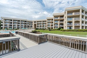 A hotel with multiple balconies, a swimming pool, and a deck area.