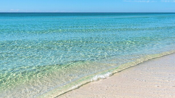 Uma praia com águas turquesa cristalinas e areia dourada.