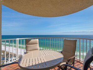 Enjoy ocean views from this balcony with a round table and two chairs.