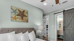 Ein Schlafzimmer mit einem großen Bett, einem Deckenventilator und einer Wanddekoration mit einem Seestern.