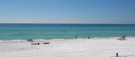 A beach with a sandy shore, a clear blue sky, and a calm sea.