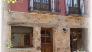 A two-story building with a stone facade, a wooden door, and a balcony with a metal railing. - La Noguera de Socasa for 14 people (Brihuega)