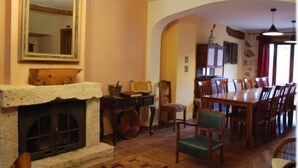 A dining area with a fireplace, wooden chairs, and a table. - La Noguera de Socasa for 14 people (Brihuega)