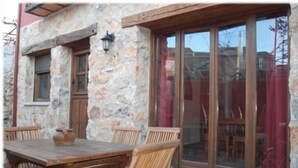 A stone building with a wooden table and chairs, a window, and a door. - La Noguera de Socasa for 14 people (Brihuega)