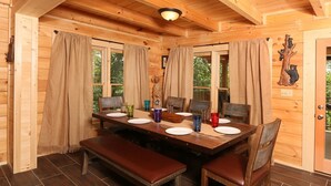 Ein Esszimmer aus Holz mit einem großen Tisch, gedeckt für vier Personen, Bänken und Vorhängen.