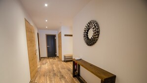 A hallway with wooden flooring, a wooden bench, and a decorative wall piece.