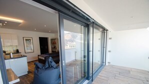 A modern interior with a glass sliding door leading to a balcony, a kitchen area, and a seating area with a bean bag.