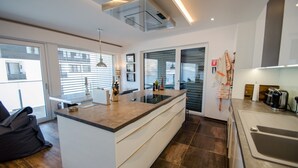 A modern kitchen with a central island, large windows, and a view of the city.