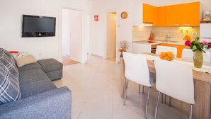 A modern living room with a grey sofa and a flat-screen TV mounted on the wall. - Apartment IVA with a sea view (Krk)