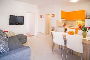 Uma sala de estar moderna com um sofá cinzento e uma TV de tela plana presa na parede.