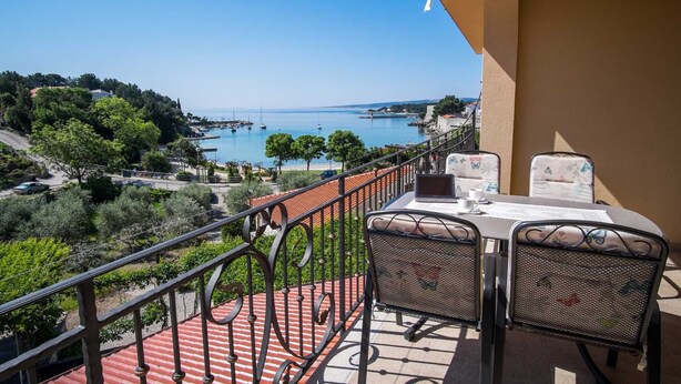 A balcony with a table and chairs overlooking a coastal view. - Apartment IVA with a sea view (Krk)