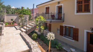 A two-story building with a stone staircase leading to a balcony. - Apartment IVA with a sea view (Krk)
