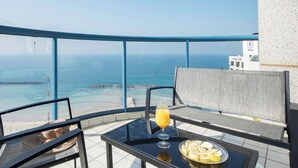 En balkon med et bord, et glas appelsinjuice og en tallerken med citronskiver.