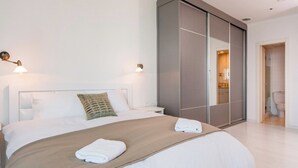 Et hotelværelse med en stor seng, et natbord, et klædeskab og et badeværelse, der kan ses gennem en åben dør.