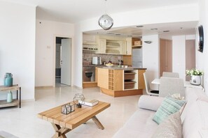 A modern living room with a wooden coffee table, a sofa, and a kitchen area with wooden cabinets and a built-in island.