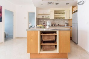 Una cocina moderna con una isla central, estantes empotrados y un refrigerador.
