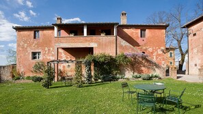 A rustic building with a garden patio, a pergola, and a small table with chairs. - Montestigliano, an authentic farmhouse in the heart of Tuscany, is an oasis of peace and beauty that offers its guests refined residences and an enchanting view (Rosia - Sovicille)