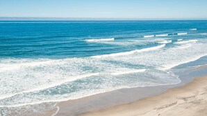 A beach with waves and a clear sky. - Promo! Oceanfront Condo - Private Hot Tub, WiFi, HDTV and Pool! (Lincoln City)