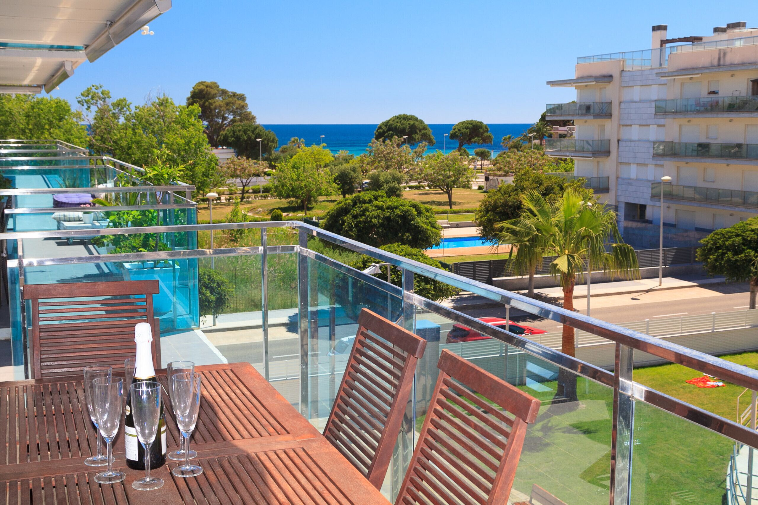 A balcony with a table, chairs, and a bottle of champagne.