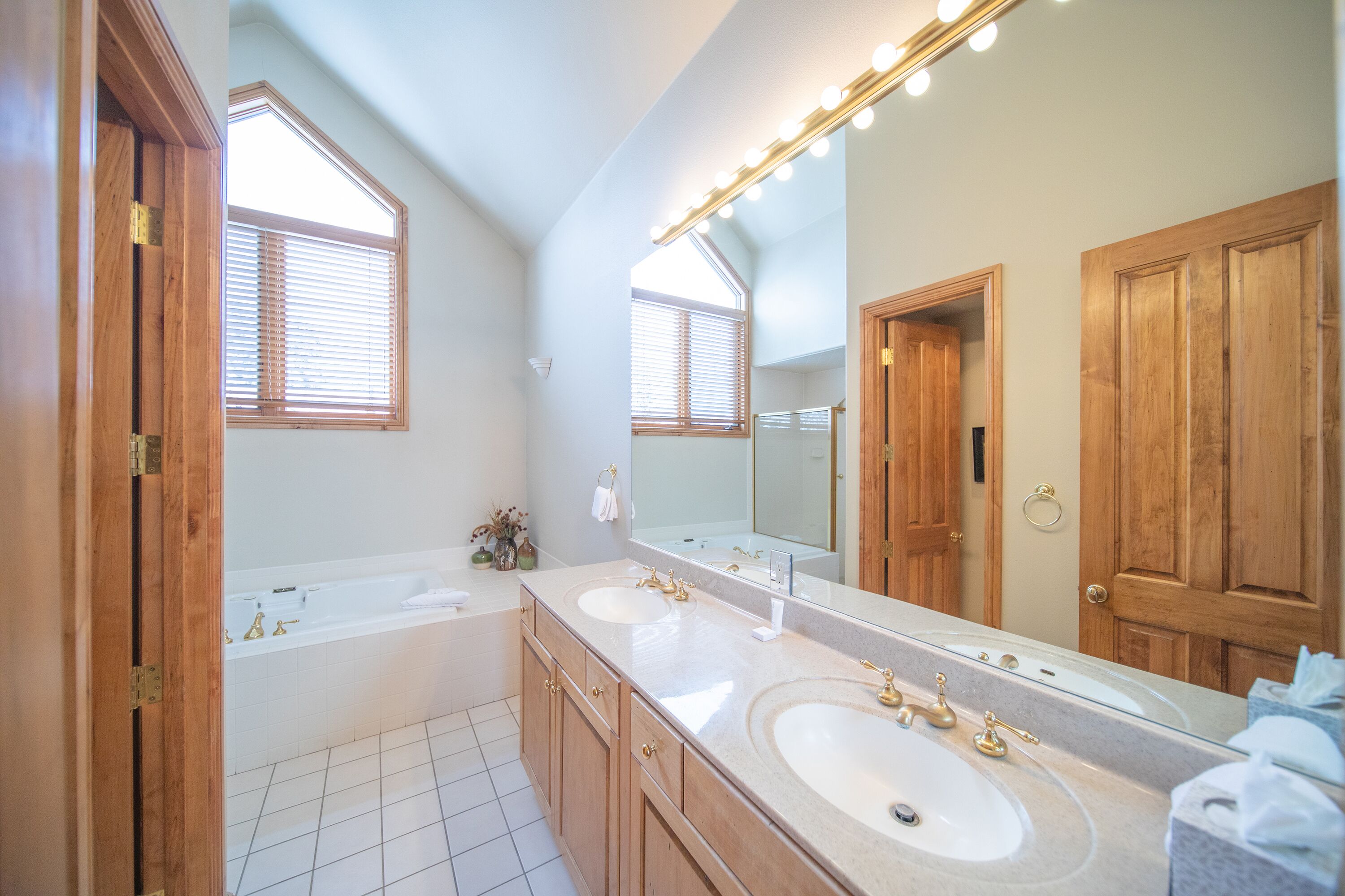 A bathroom with two sinks, a large mirror, and wooden cabinets.