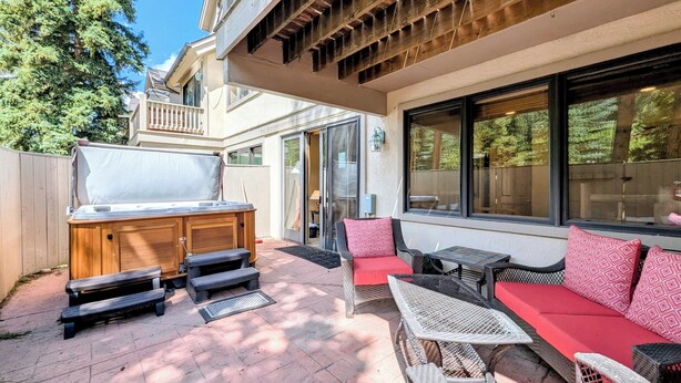 An outdoor patio with a grill, seating, and a view of the house.