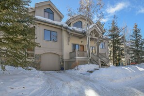 Une maison à deux étages, dont le toit est recouvert de neige et dont on peut voir la porte du garage.