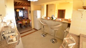 A kitchen with two bar stools, a refrigerator, and a dining area with a table and chairs. - Apartment in Lucca with 3 bedrooms sleeps 7 (Lucca)