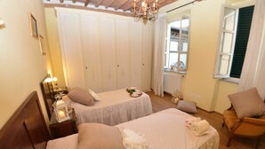 A bedroom with two beds, a chair, a table with a tray, and a window with shutters. - Apartment in Lucca with 3 bedrooms sleeps 7 (Lucca)