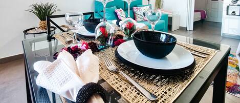 A dining area with a glass table set for four, including plates, bowls, and cutlery.