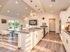 A modern kitchen with a central island, white cabinetry, and pendant lighting.