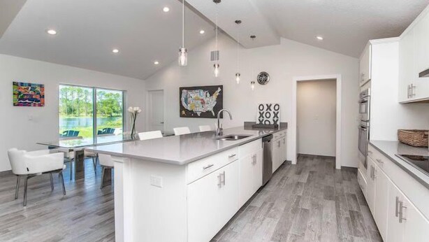 Een moderne keuken met een groot eiland, witte kasten en uitzicht op een meer.