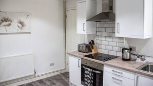 Una cocina moderna con armarios blancos, una estufa negra y un salpicadero de azulejos.