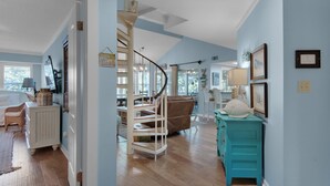 A spacious room with a wooden floor, a staircase, and a dining area with a table and chairs. - Bright and Cheerful Cottage, Updated Kitchen, Large Flat Screen TV (Miramar Beach)