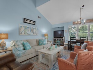 A living room with a light blue wall, a sofa, a coffee table, and a television.