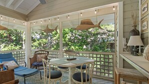 A covered patio with a table and chairs, a sofa, and a lamp. - Bright and Cheerful Cottage, Updated Kitchen, Large Flat Screen TV (Miramar Beach)